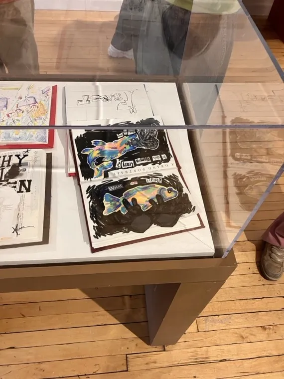 Ophir's collage sketchbooks displayed in a glass exhibition case